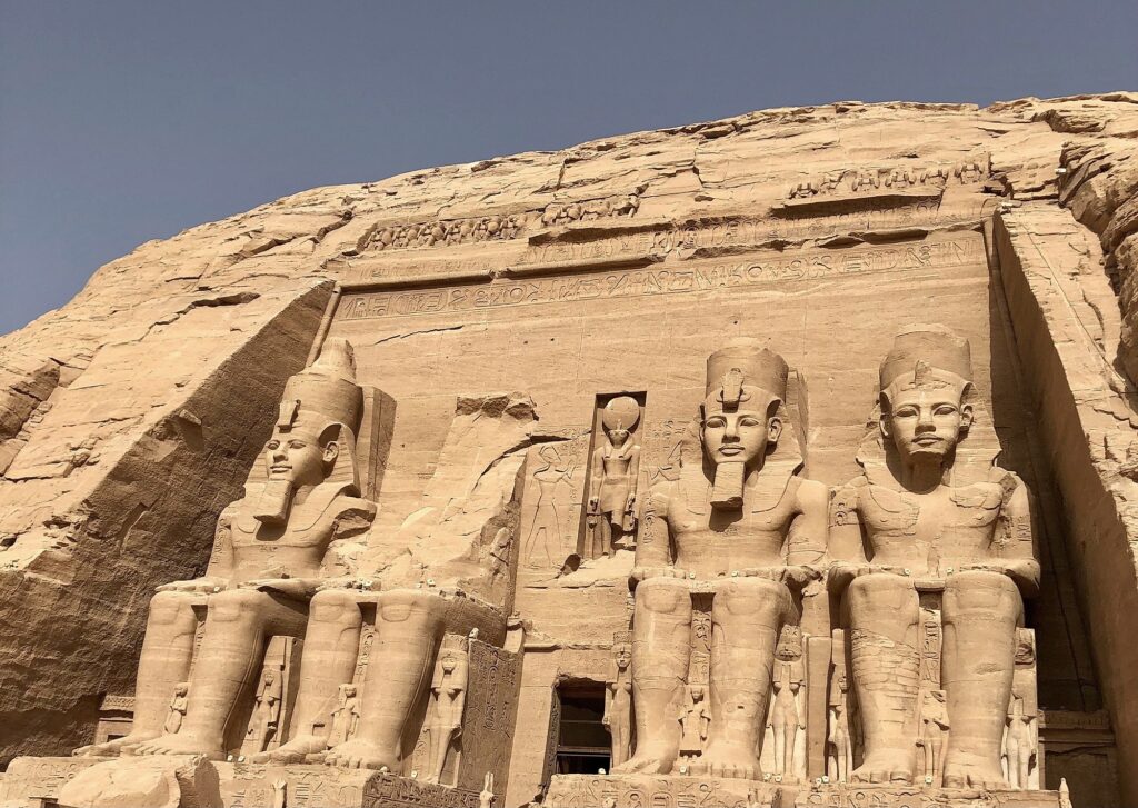 Entrance to the Great Temple of Ramses II shown in full sun, entrance is flanked by two imposing statues on either side.